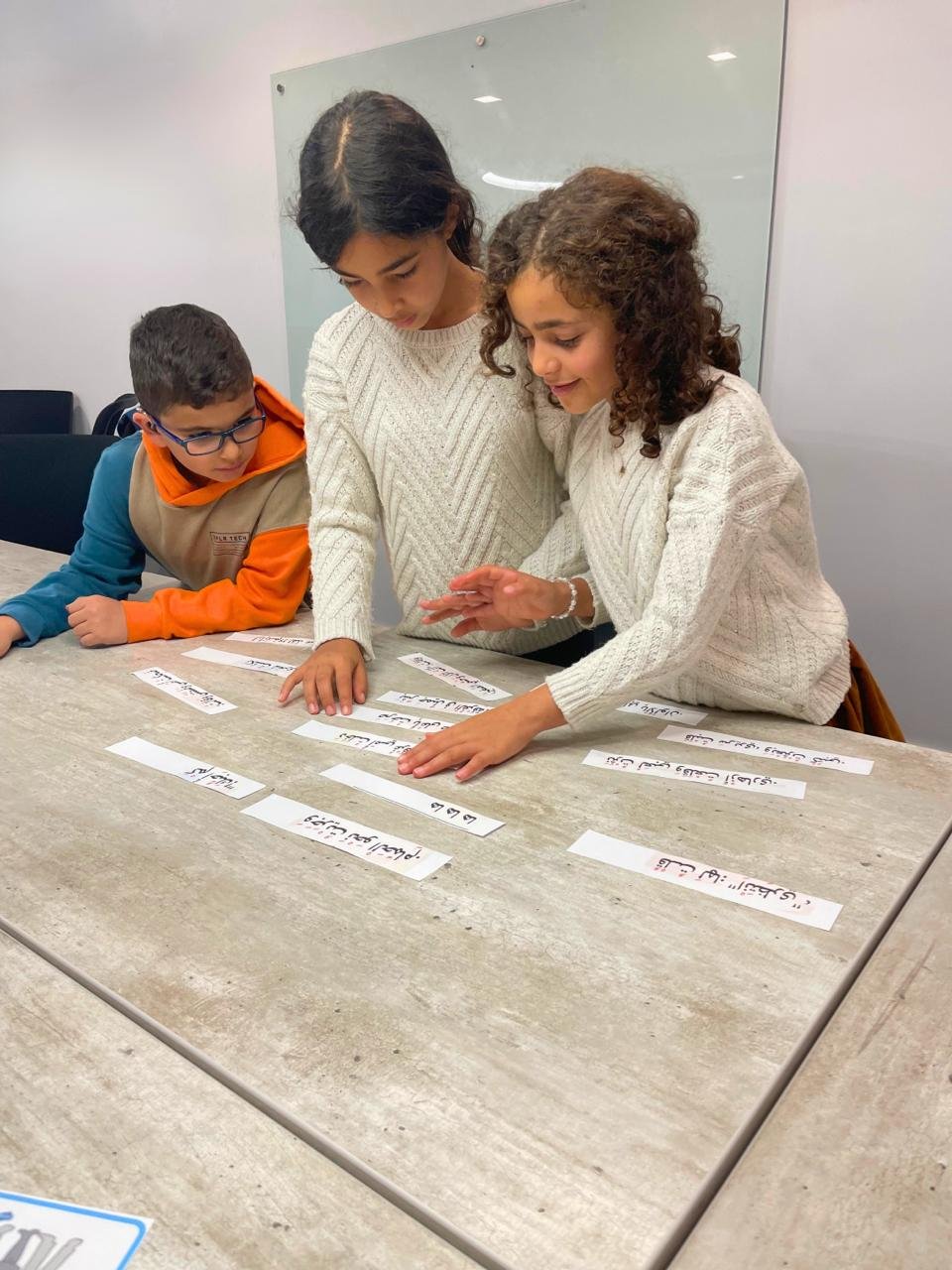 Children practicing Arabic words together at a table